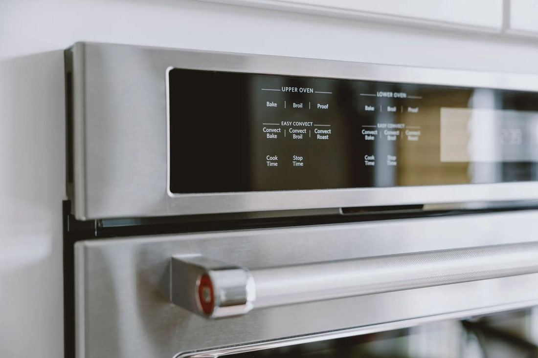 Stainless steel oven with digital display showing cooking options: Bake, Broil, Proof, Convection settings. Sleek modern kitchen setting.